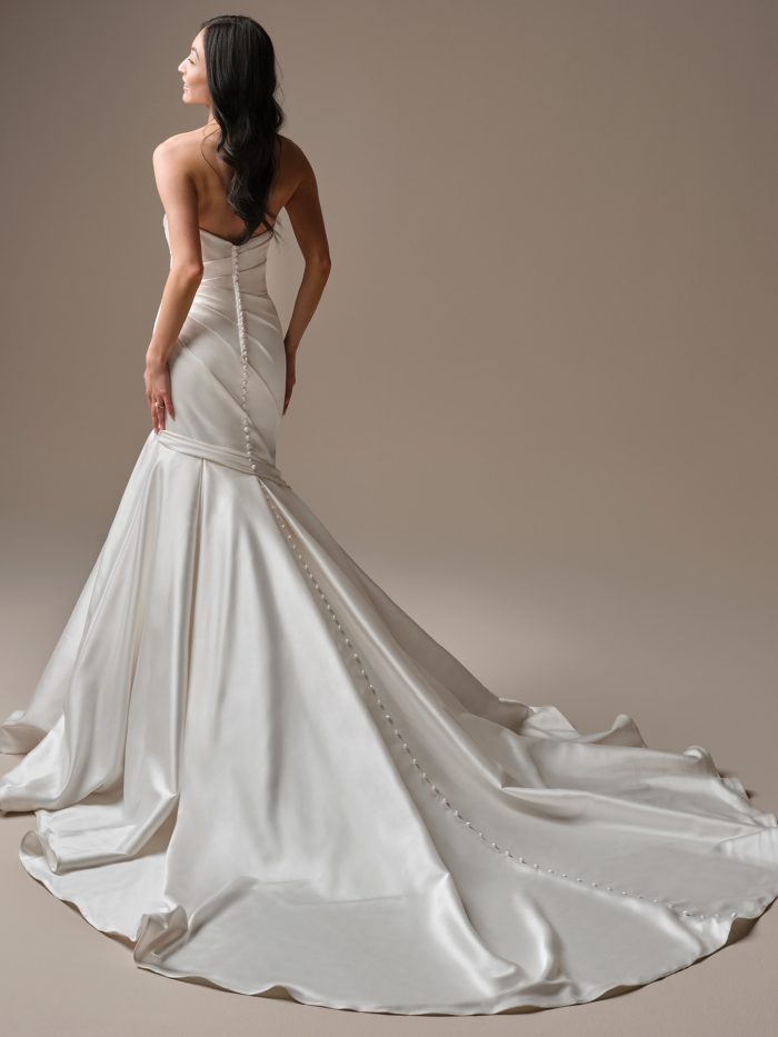 Emelina by Maggie Sottero strapless satin fit-and-flare wedding dress featuring covered button back detail and a sweeping train with soft draping