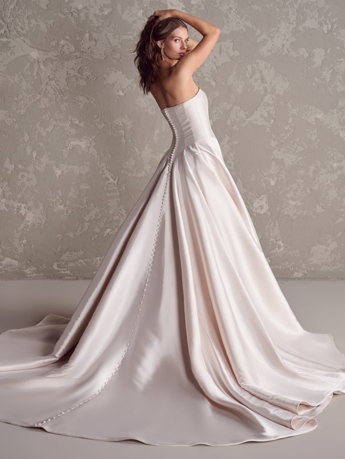 Emmanuelle by Maggie Sottero strapless satin ballgown wedding dress featuring covered button back detail and dramatic train