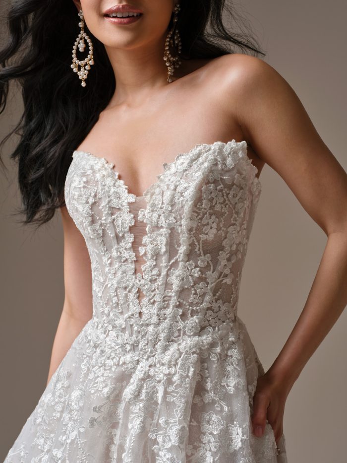 Memphis by Maggie Sottero strapless wedding dress featuring plunging illusion neckline, sheer corset bodice, and intricate floral lace detail