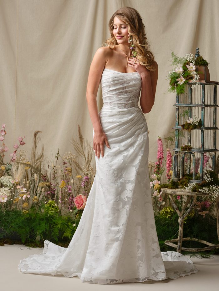 Kendall by Rebecca Ingram strapless sheath wedding dress with printed organza, ruched bodice, and soft fitted silhouette